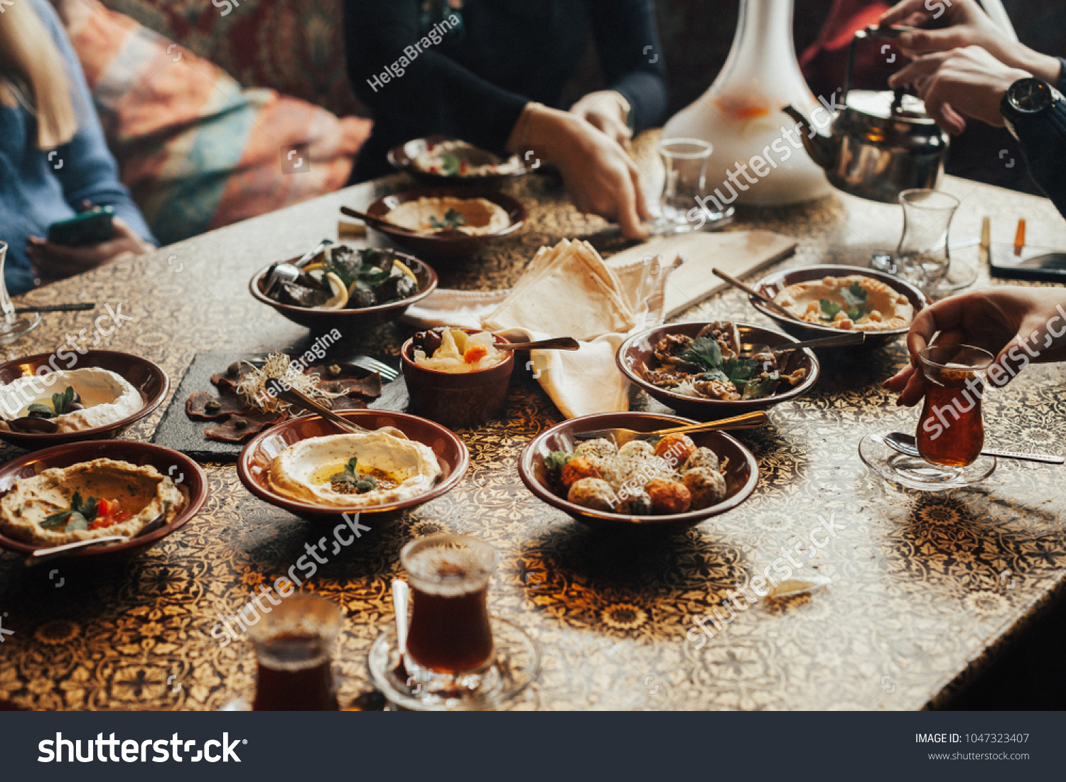Lebanon cuisine served in restaurant. A young company of people is smoking a hookah and communicating in an oriental restaurant. Traditional meze lunch #1047323407