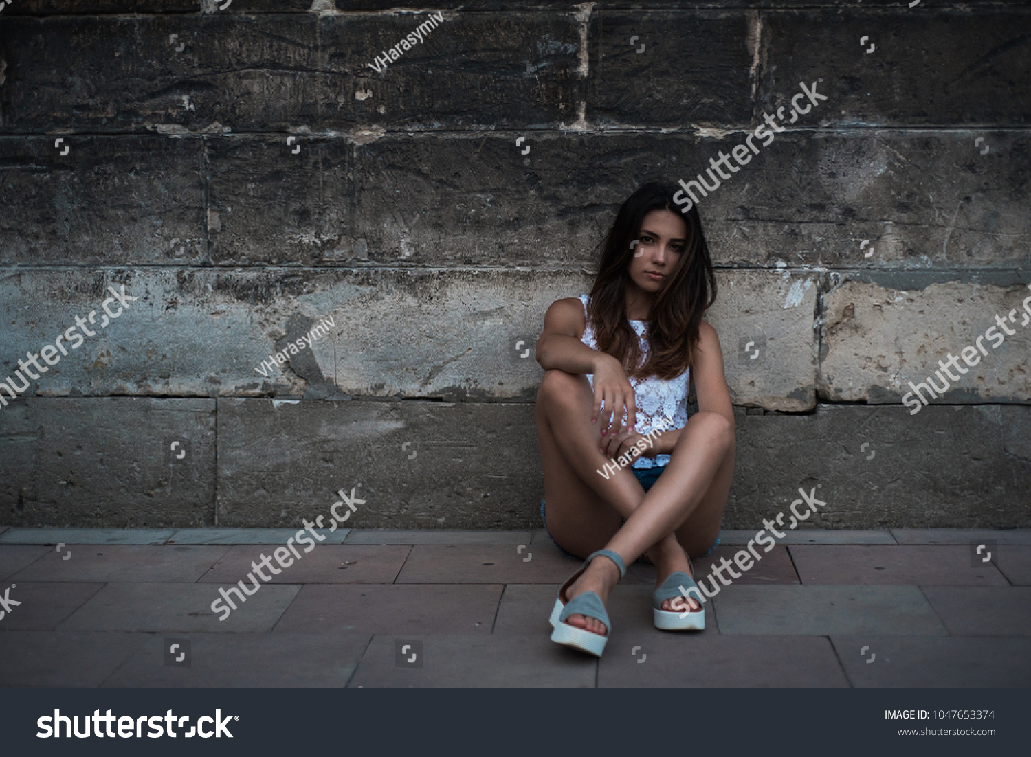 Girl with a black cap. Portrait of a girl on the background of the old wall. #1047653374