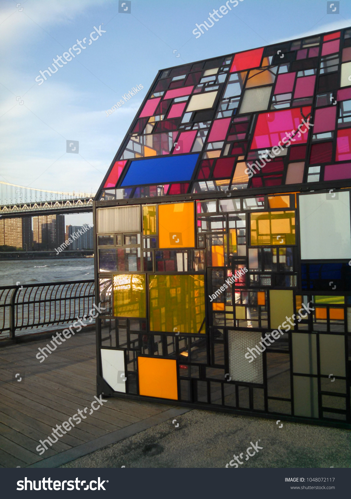 Brooklyn, NY, USA May 25, 2015 A stained glass sculpture, Kolonihavehus by Tom Fruin sits in Brooklyn Bridge Park, overlooking the East River and Manhattan #1048072117