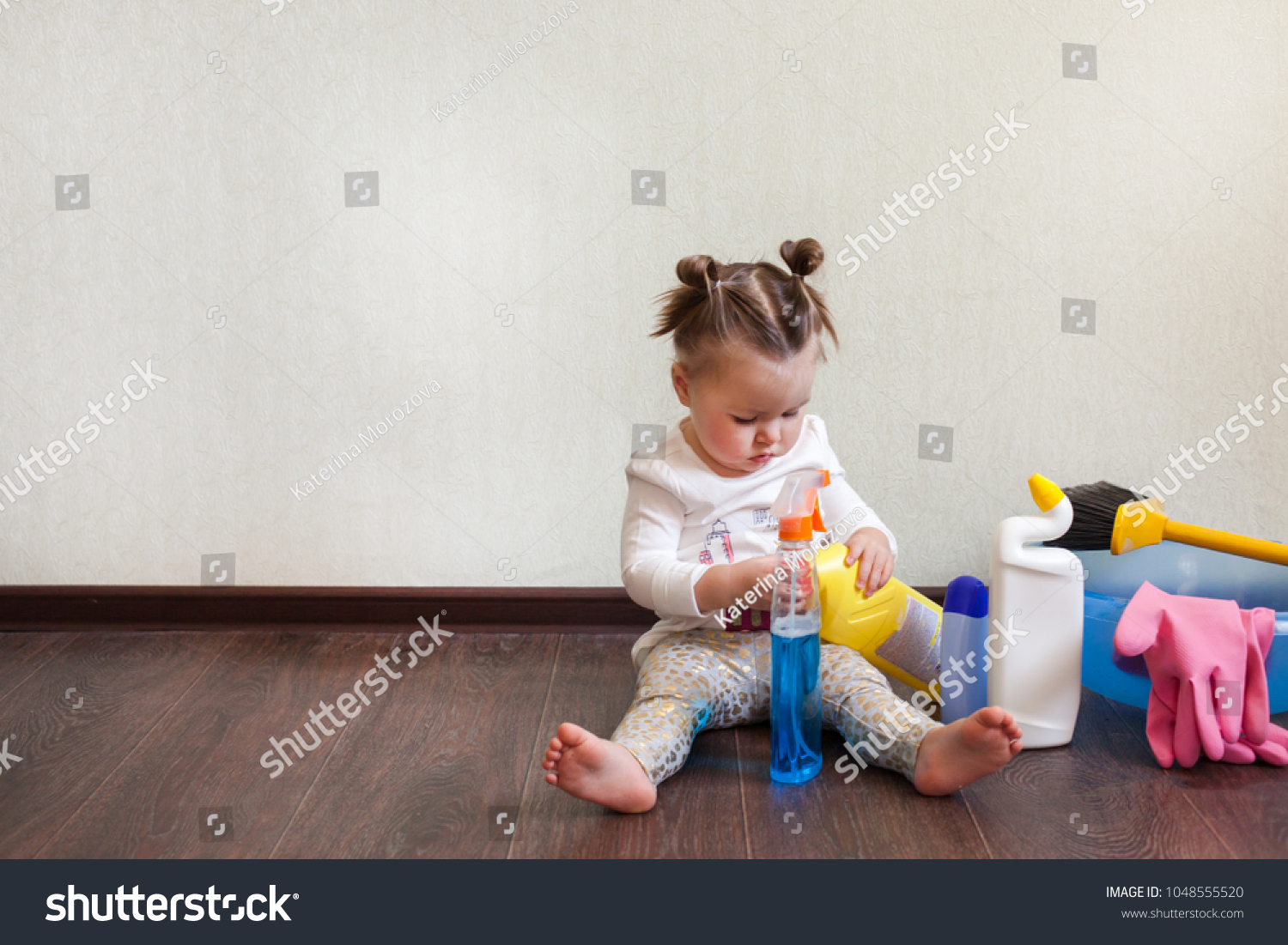Tidy up concept, stay home, child playing with bottles with household chemicals sitting on the floor of the house #1048555520