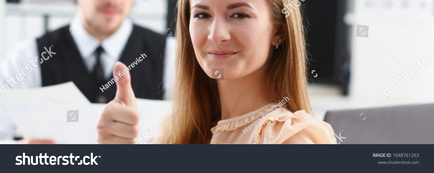 Beautiful smiling woman showing OK or approval sign with thumb up in creative people office closeup. High level and quality service job offer excellent education advisor serious business concept #1048761263
