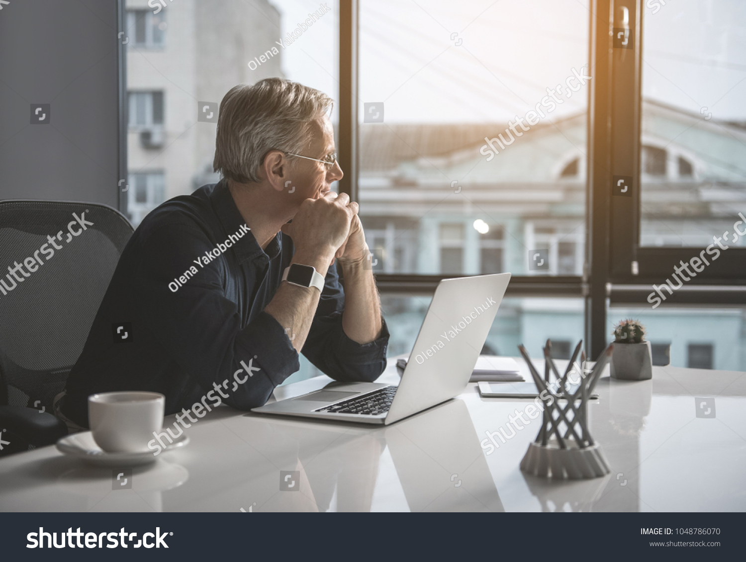Pensive mature businessman having job with laptop while looking at window. Contemplative employer concept #1048786070