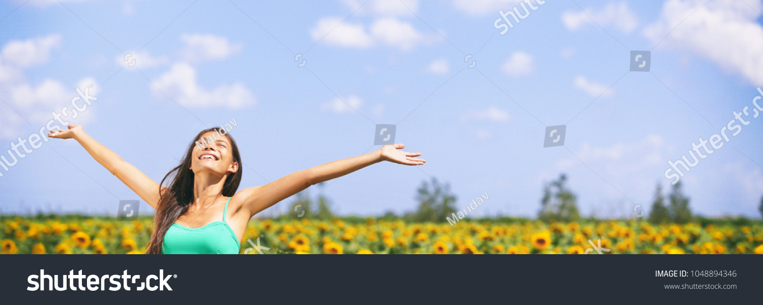 Summer girl happy in sunflower flower field for spring. Cheerful multiracial Asian Caucasian young woman joyful with arms raised up. Panoramic landscape banner. #1048894346