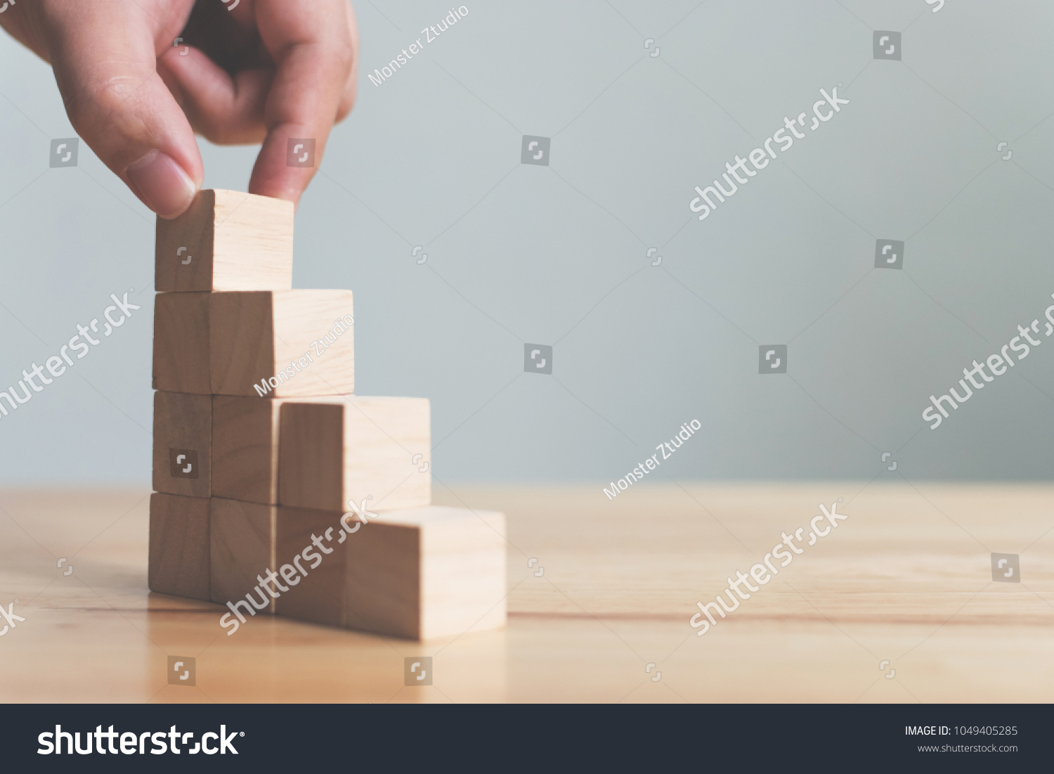 Hand arranging wood block stacking as step stair on wooden table. Business concept for growth success process. Copy space #1049405285