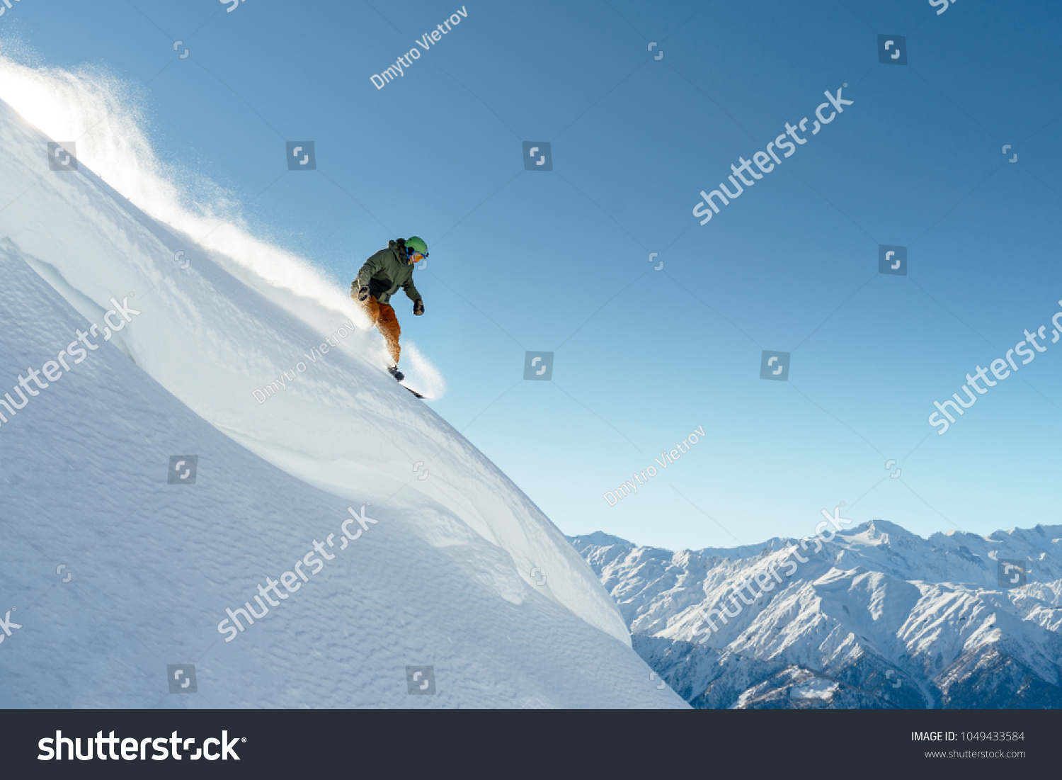 snowboarder rides on a steep mountainside on a beautiful landscape #1049433584