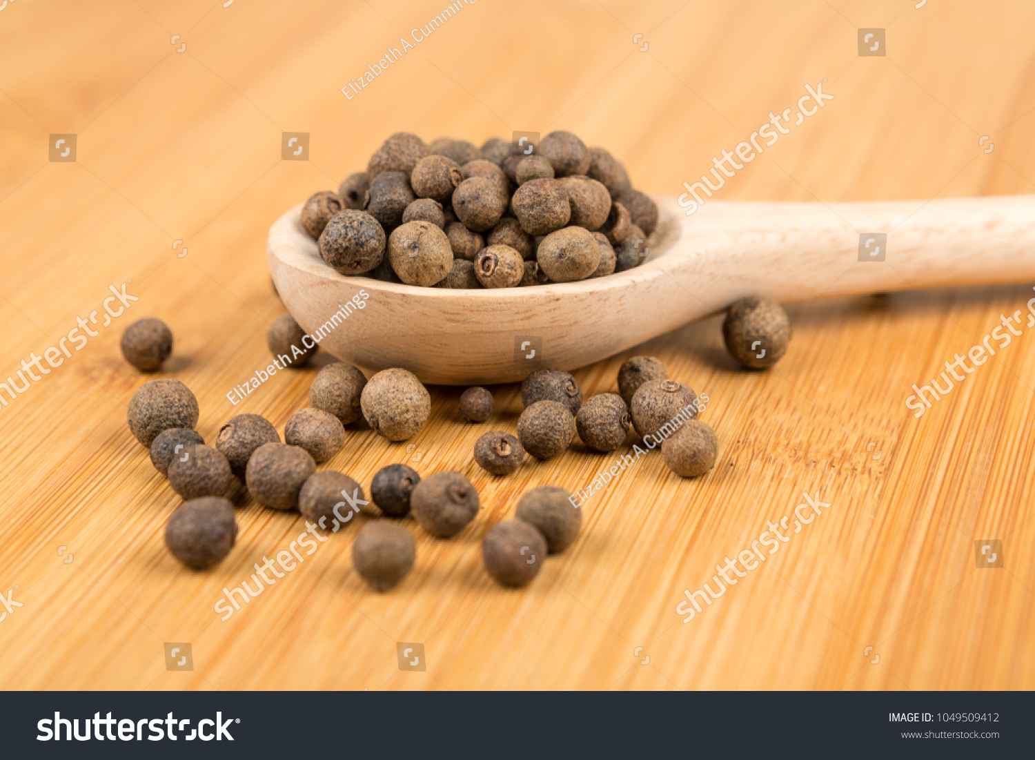 Dried whole allspice on a wood background #1049509412