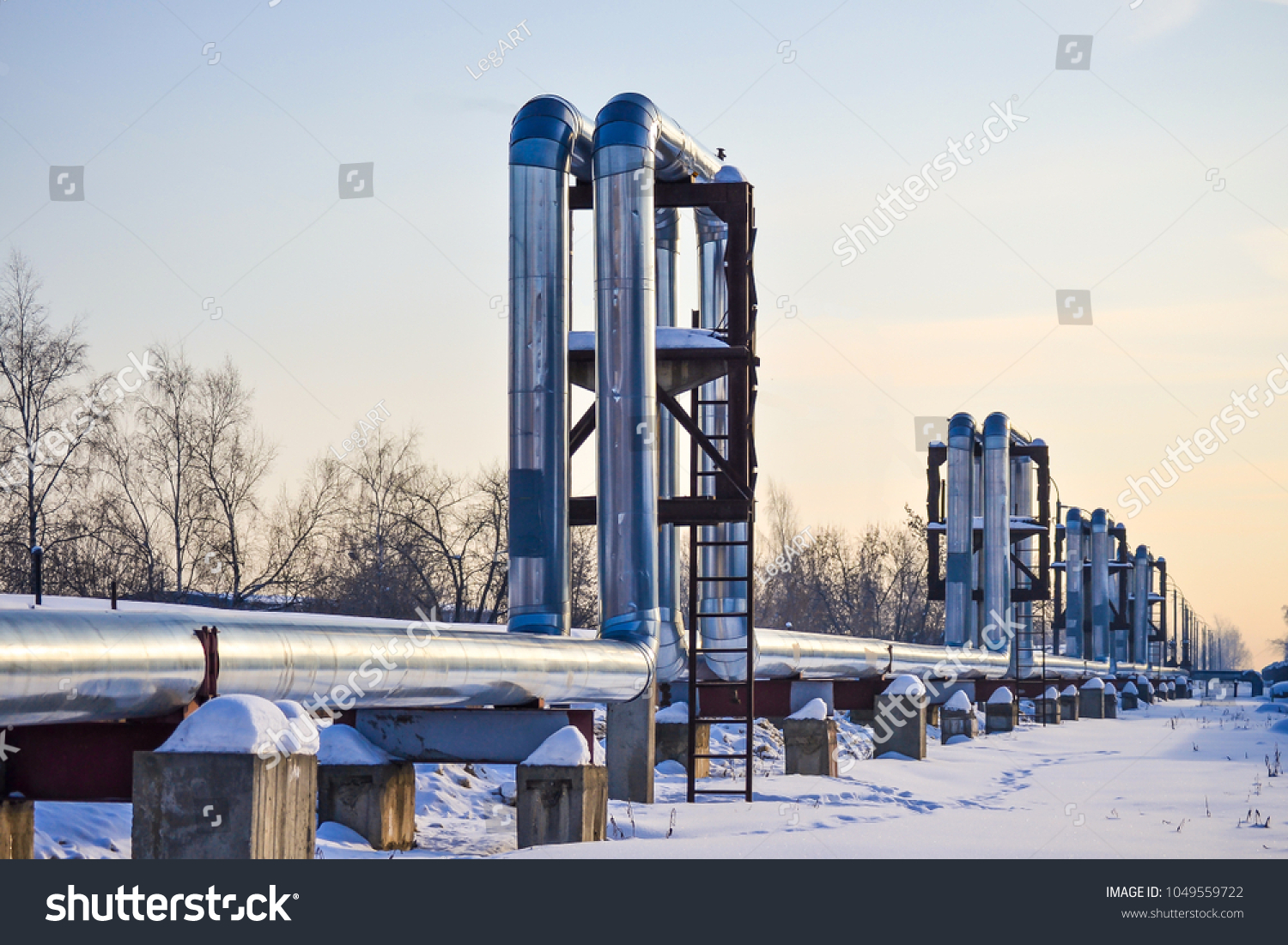 Overground heat pipes. Pipeline above ground, conducting heat for heating the city. Winter. Snow. #1049559722