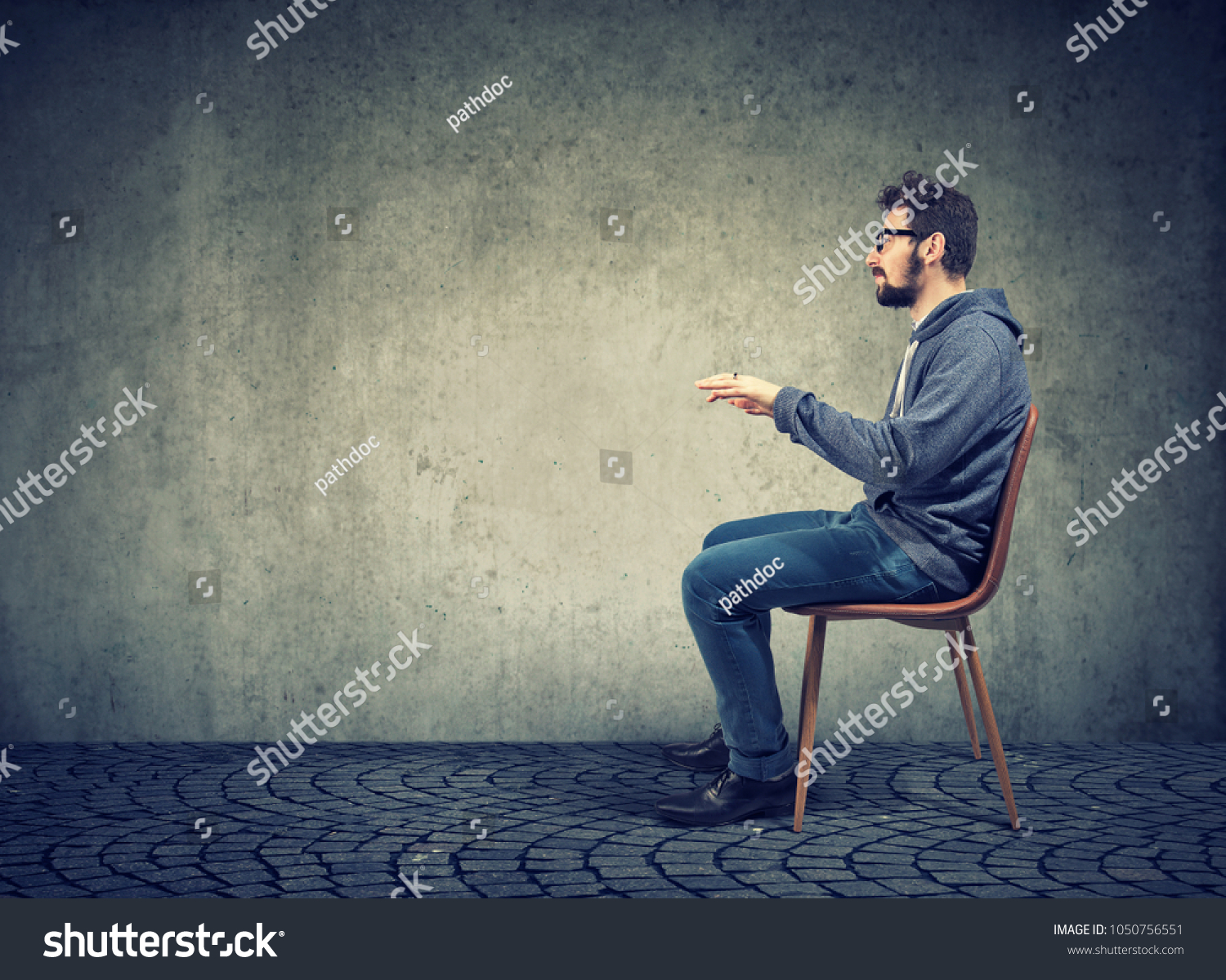 Side view of casual man sitting at invisible table pretending to type on computer.  #1050756551