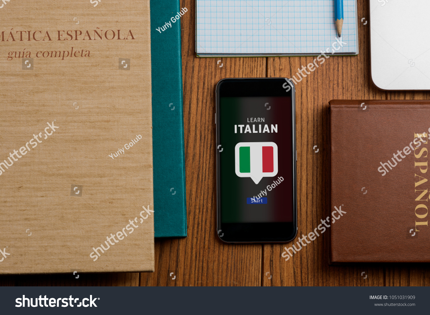 App and textbooks for learning Italian. Books, phone and notepad on student's workplace. Education, foreign languages. #1051031909