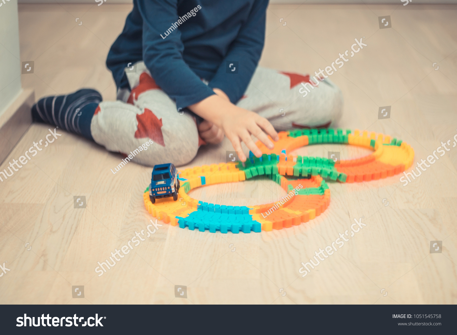 Unrecognizable boy making a trail and playing with car toy on the floor. #1051545758