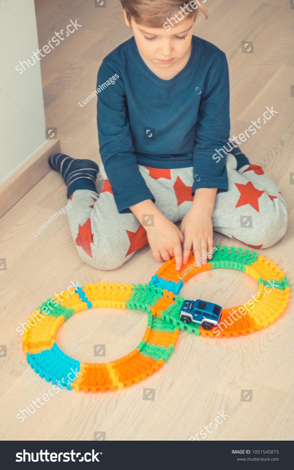 Little boy sitting on the floor and playing with car toy at home.  #1051545815