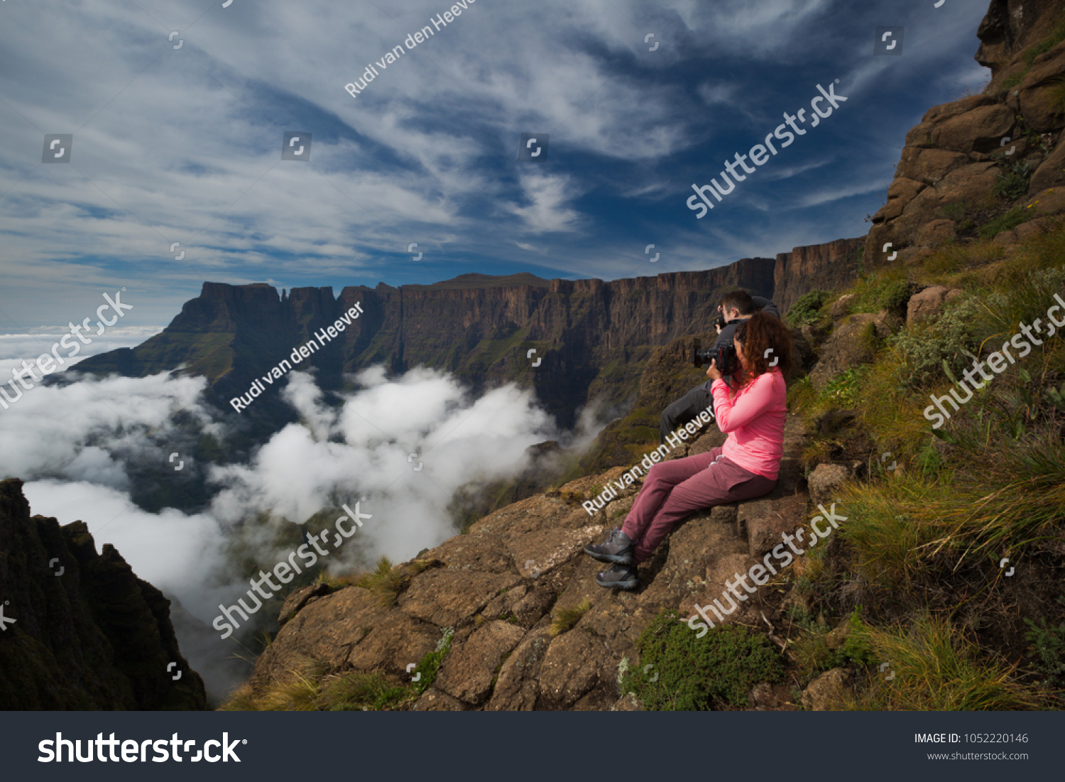 Two photographers photograph the beauty of the Drakensberg Amphitheatre from the Witches Viewpoint in the Ukhahlamba Drakensberg Park, South Africa. A low cloud inversion and high clouds and blue sky. #1052220146