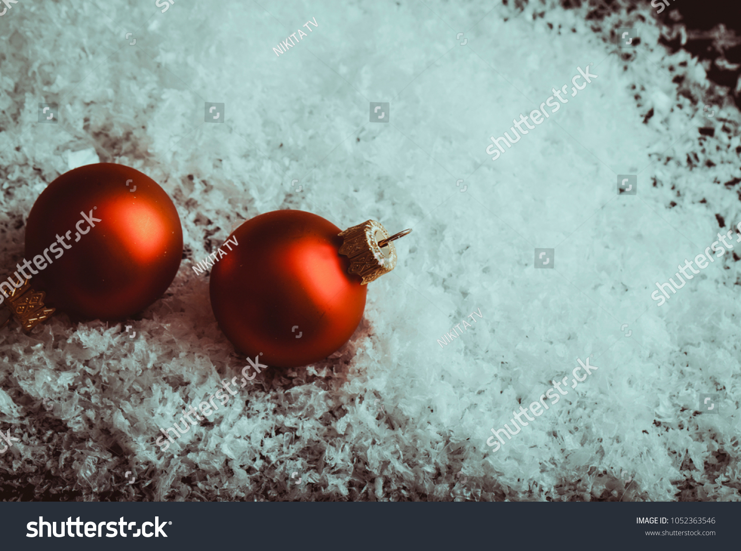 Two Small red Christmas balls. Two Red mate Christmas balls in snow and blur photo studio background table #1052363546
