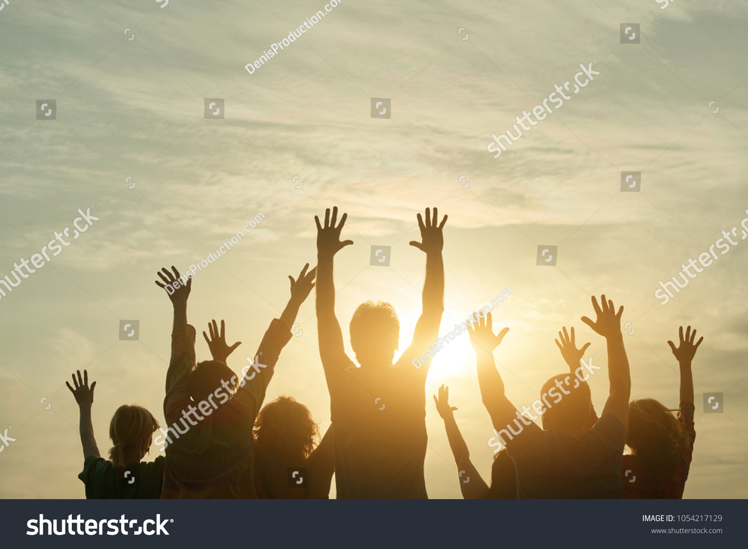 People silhouette at sunset. Happy fans of a rock group outdoor. Human body over natural colorful sky background. #1054217129