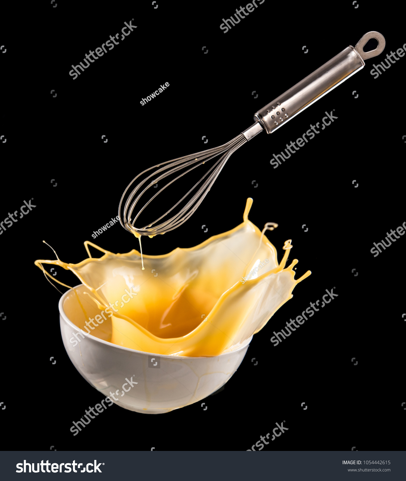 Wire whisk with Egg splash in bowl isolated on black background, motion action. #1054442615