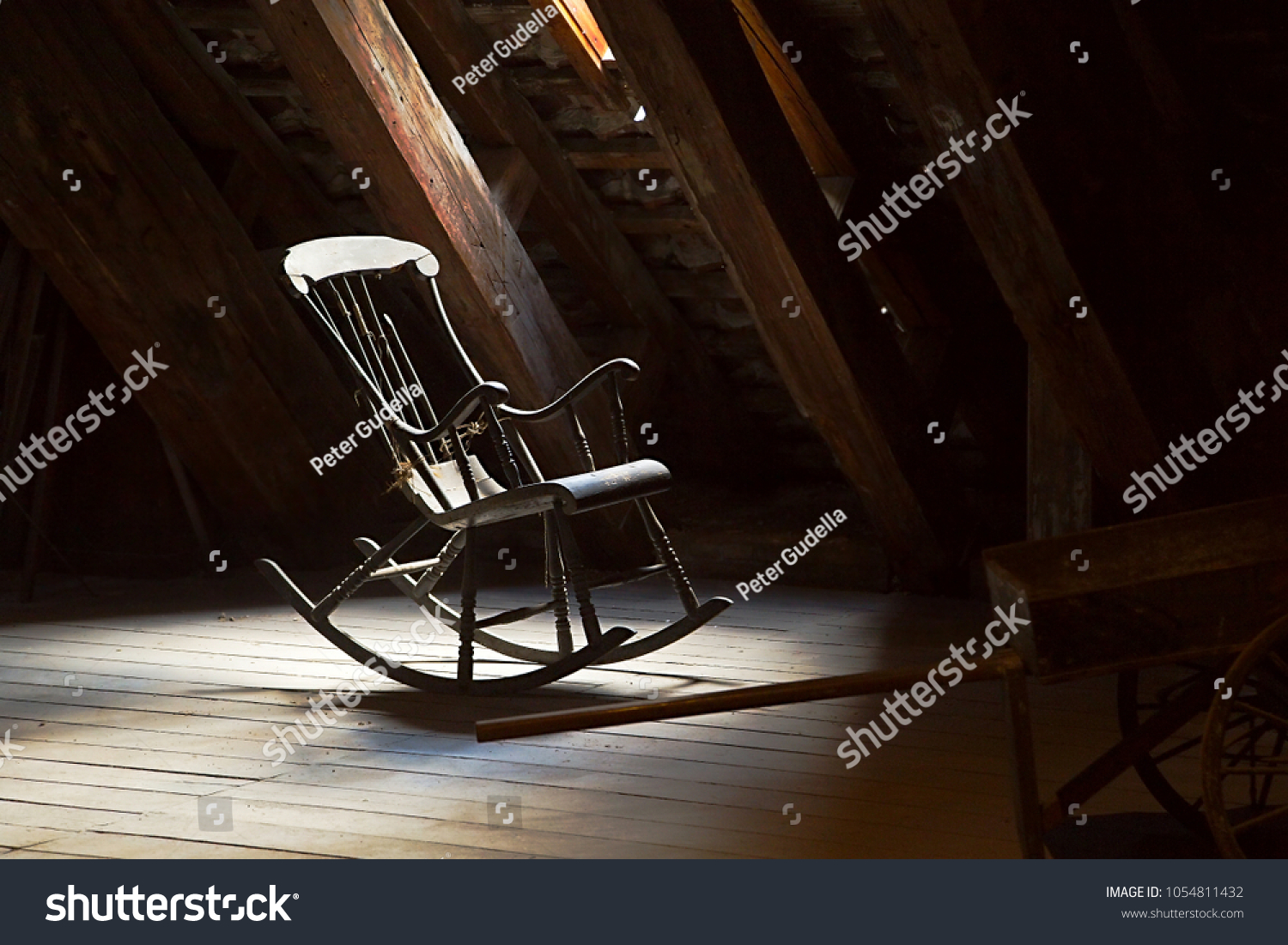 Old rocking chair on a dim attic #1054811432