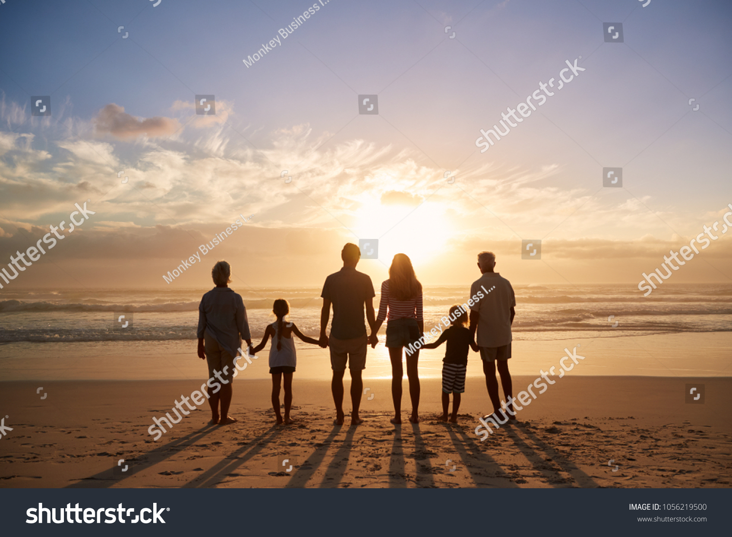 Rear View Of Multi Generation Family Silhouetted On Beach #1056219500