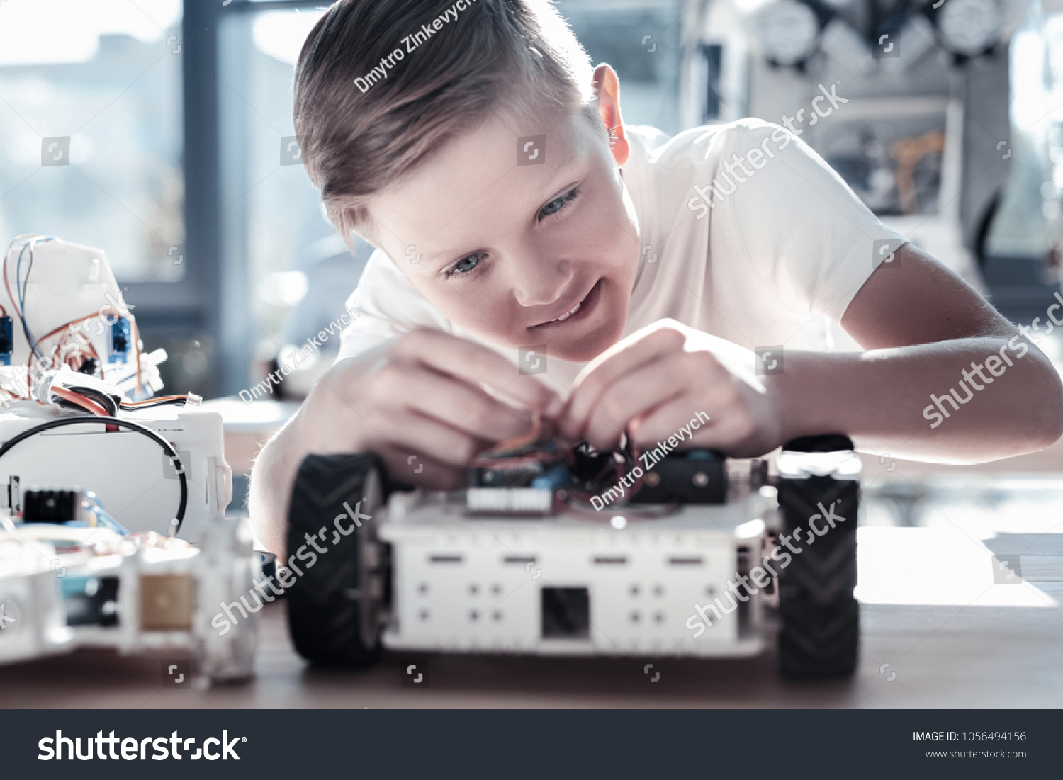 This is so interesting. Selective focus on a focused preteen boy focusing his attention on a robotic machine while enjoying the process of working on a school technological process. #1056494156