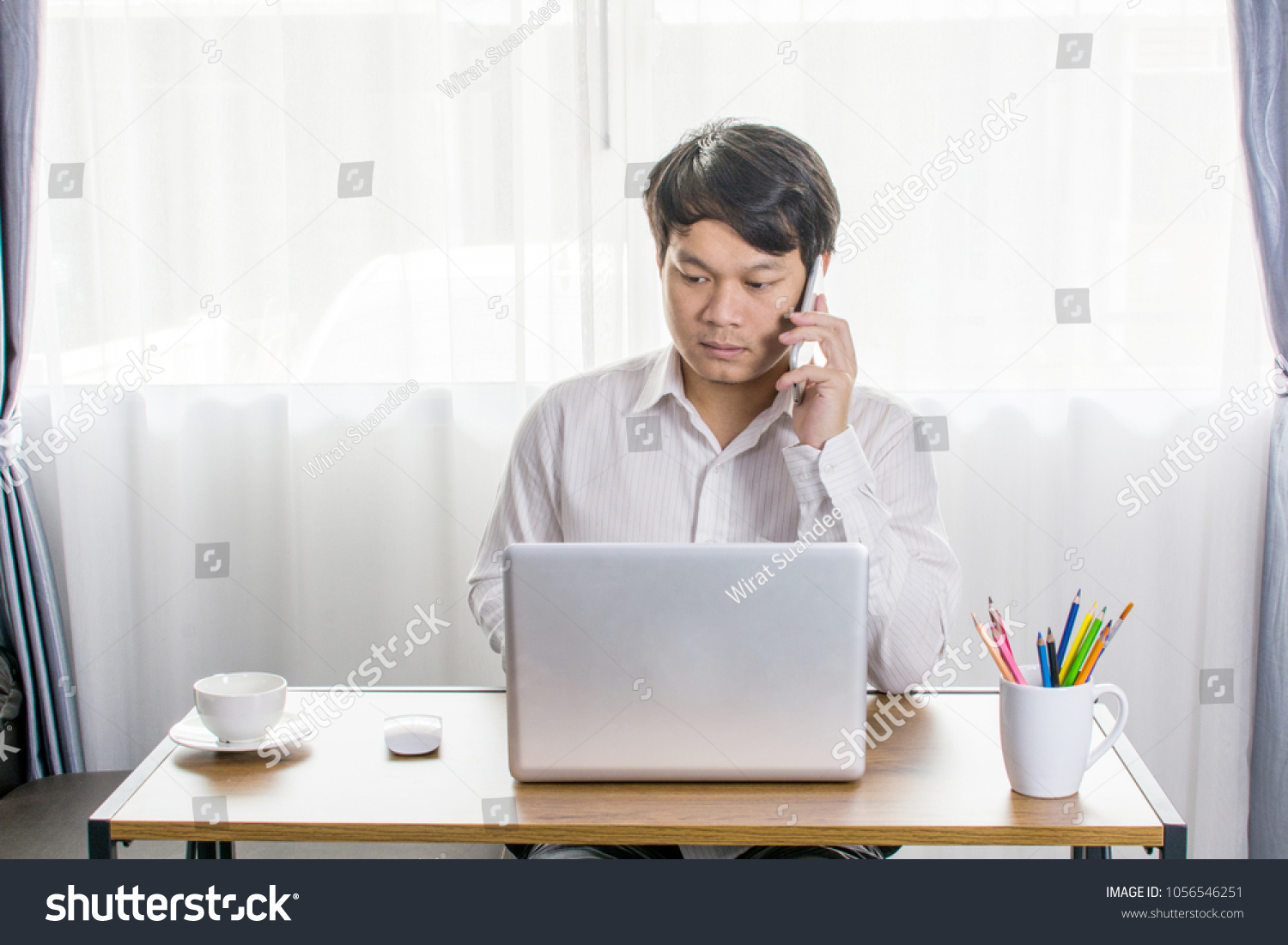 View workspace mockup concept with laptop on home office or studio. Close up of man working determine lifestyle concept. Mock up workplace on wooden table with Natural light. windows, East Asian Man. #1056546251
