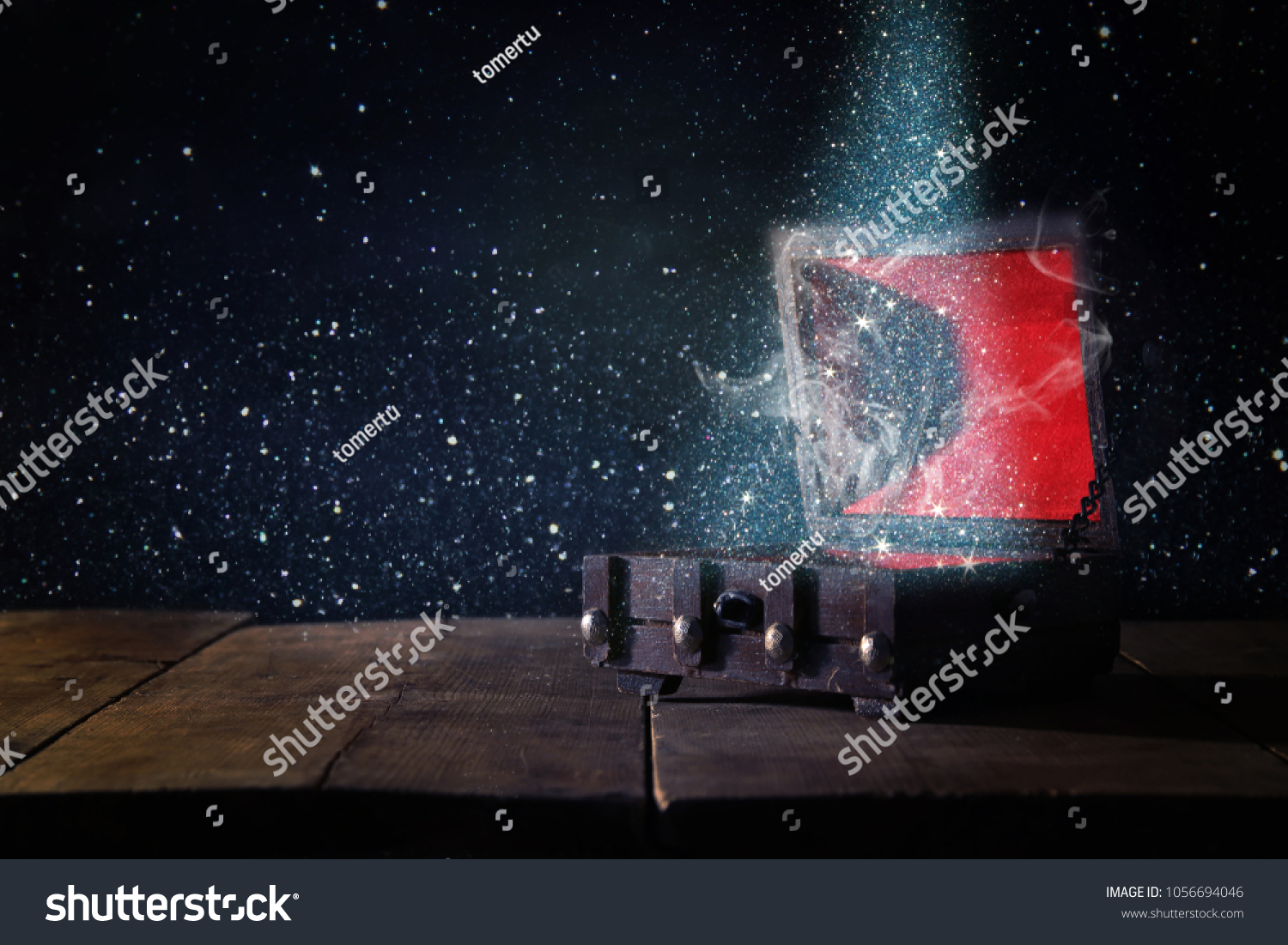 Image of mysterious treasure chest with glitter light and smoke over wooden old table #1056694046
