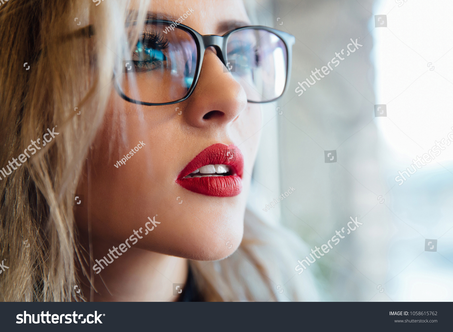 Glasses eyewear woman portrait looking away. Close up portrait of female business beautiful student woman model face. Blonde, red lips. Indoor. #1058615762