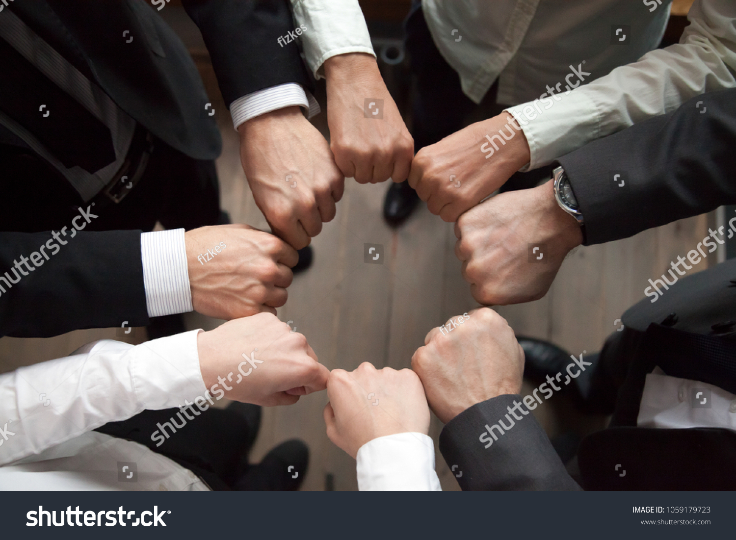 Business team or partners put fists in circle as concept of motivating engaging teambuilding activity, reliable support, help in cooperation, trust unity in collaboration teamwork, close up top view #1059179723