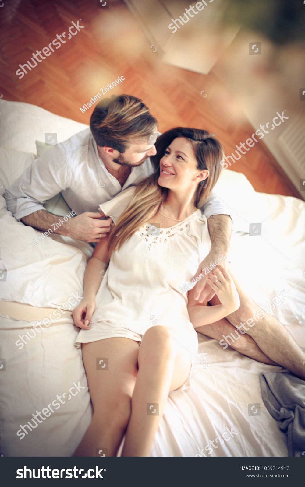 Happy young couple in bed. Space for copy. #1059714917