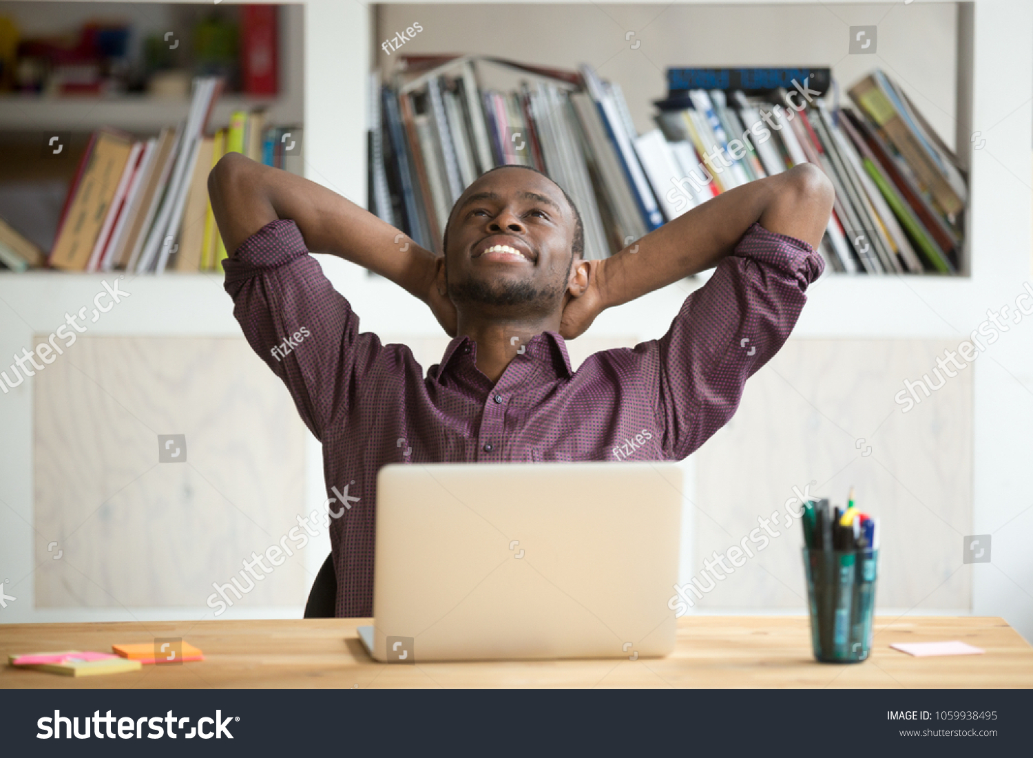 Satisfied black worker relaxing leaning in comfortable chair with hands overhead happy with finished work, successful business report and promising results. Concept of rewarding, resting and winning #1059938495
