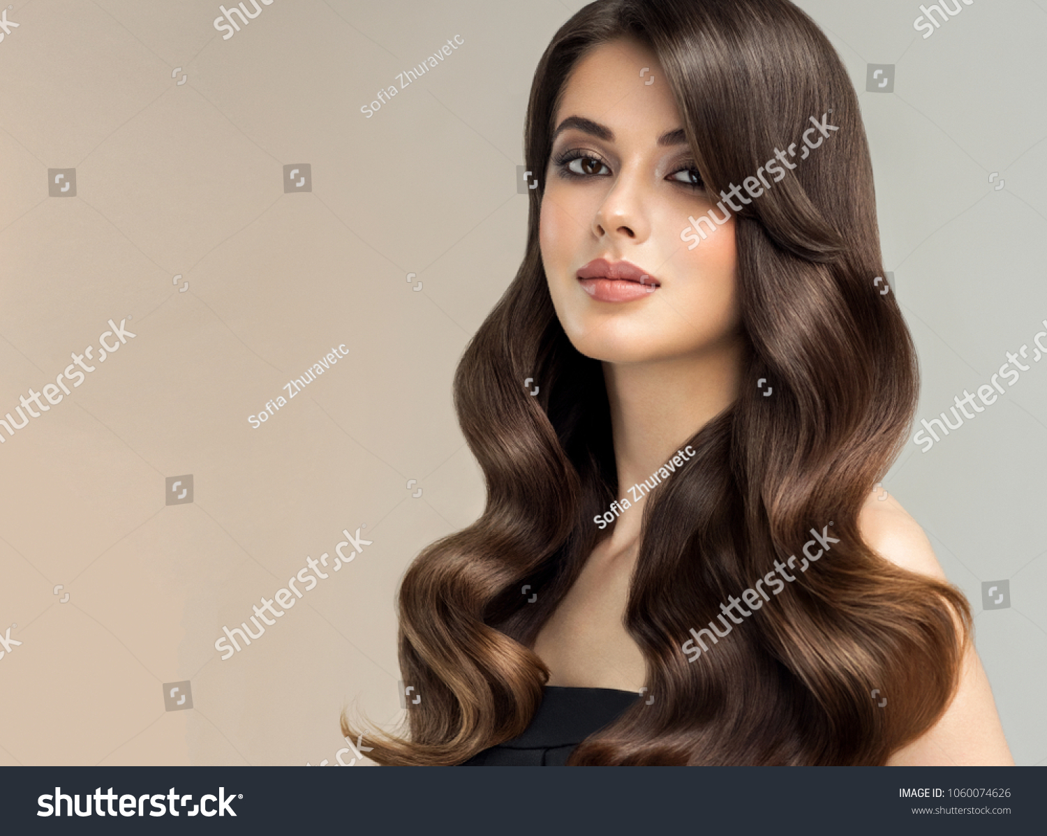 Brunette  girl with long , healthy and   shiny curly hair .  Beautiful  model woman  with wavy hairstyle   .Care and beauty #1060074626