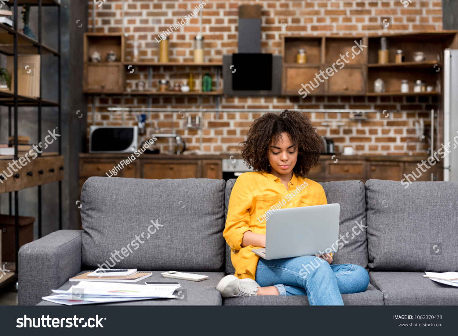 attractive young woman working working with laptop on couch #1062370478