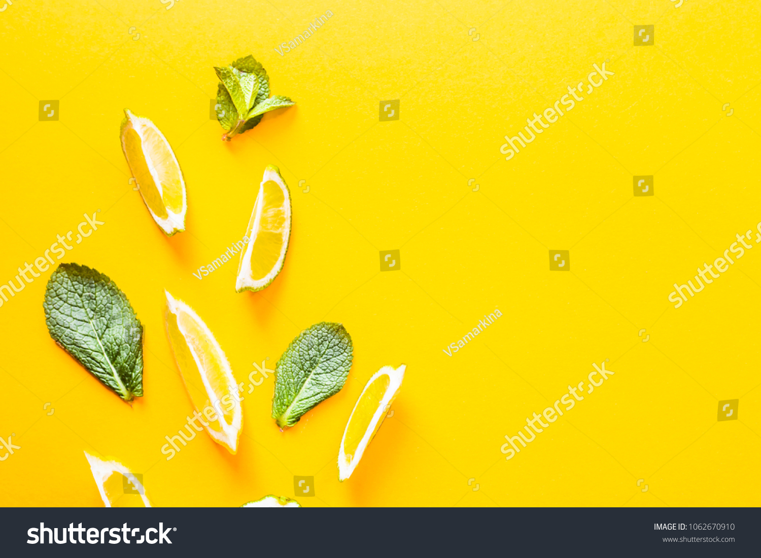 Pieces of lemon, lime and green mint leaves on a yellow background. Summer products for making lemonade. Top view, flat lay, copyspace #1062670910