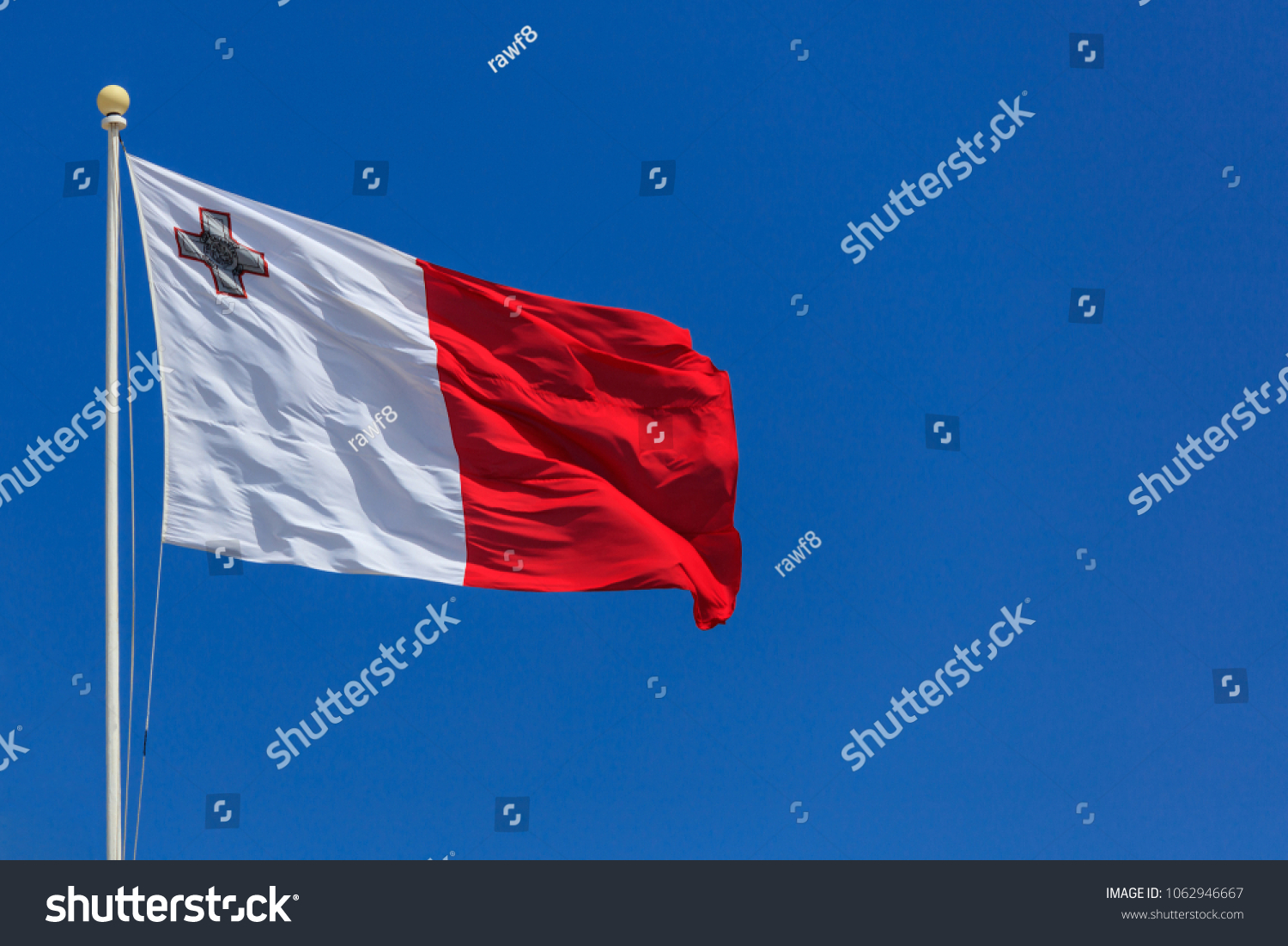 Malta flag. Malta flag on a flagpole waving on a bright blue sky background #1062946667