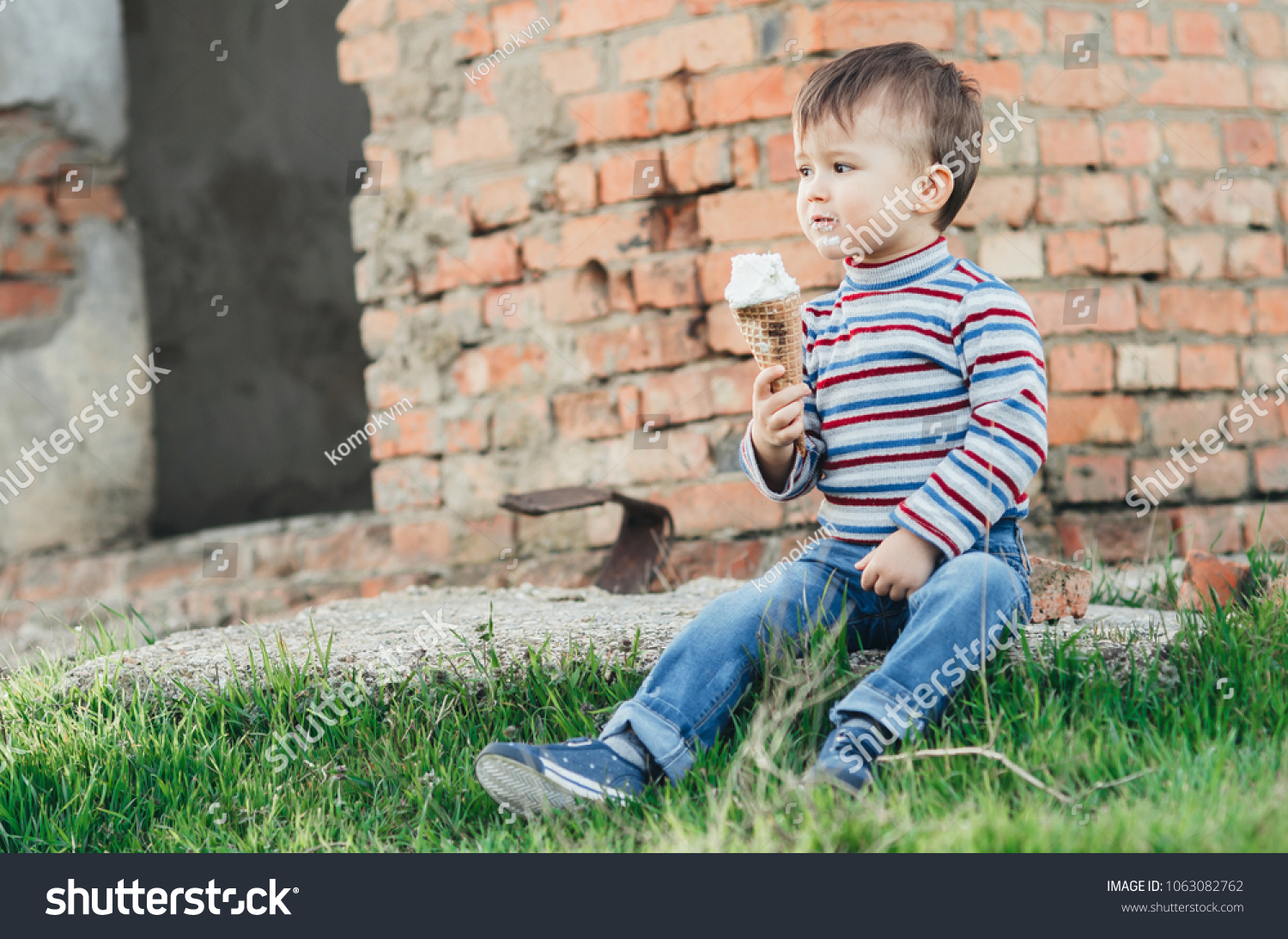 little cute boy boy boy three years eating ice cream very appetizing on brick wall background #1063082762