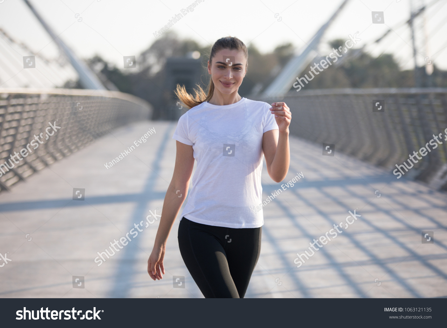 Sports woman in a white T-shirt while training on the bridge. Mock-up. #1063121135