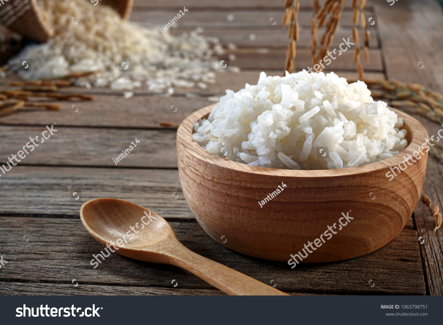 Jasmine rice in wood bowl and paddy rice on a brown wooden background beautiful Thai food #1063798751