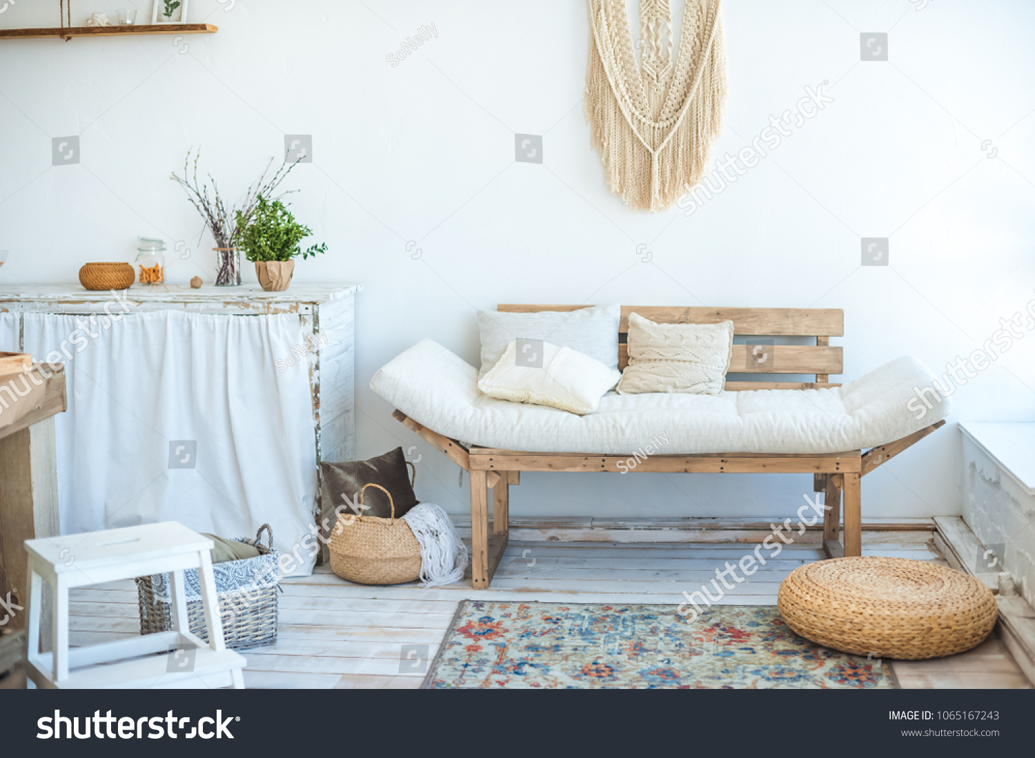 Beautiful spring photo of kitchen interior in light textured colors. Kitchen, living room with beige couch sofa, large cactus and woven macrame on the wall #1065167243