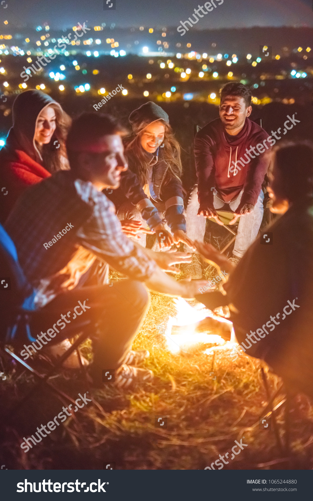 The happy people warming hands above the bonfire. evening night time #1065244880