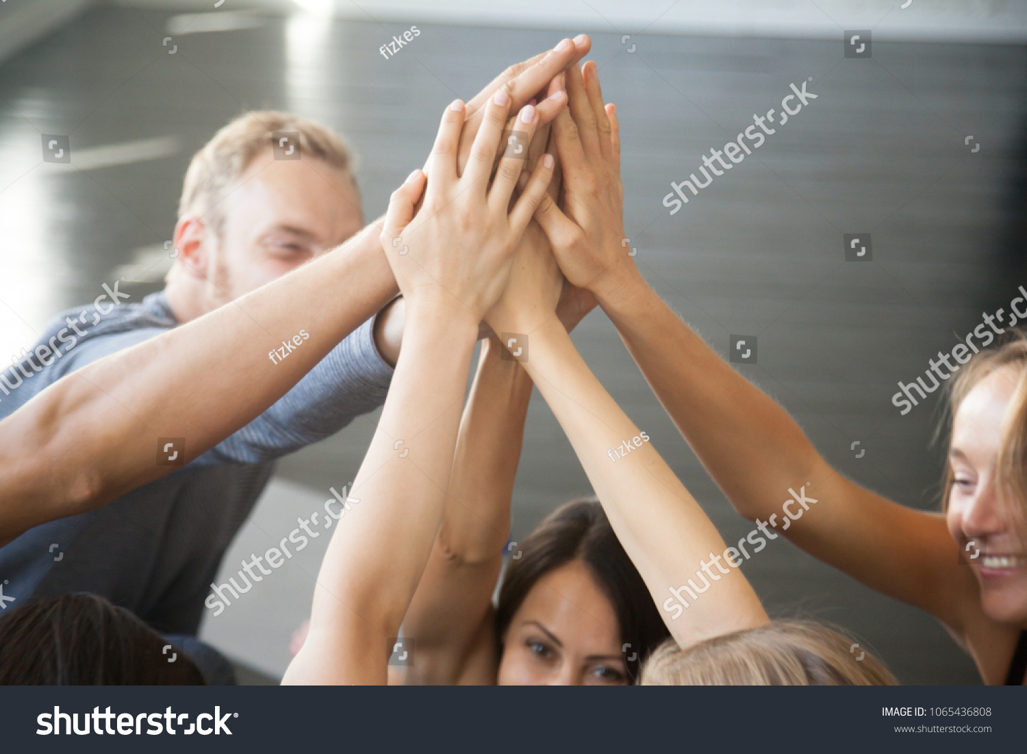 Group of fit happy people giving high five in fitness studio room, talking in a circle after seminar training. Setting goal, achieving team results. Teamwork, mindfulness, active life benefits concept #1065436808