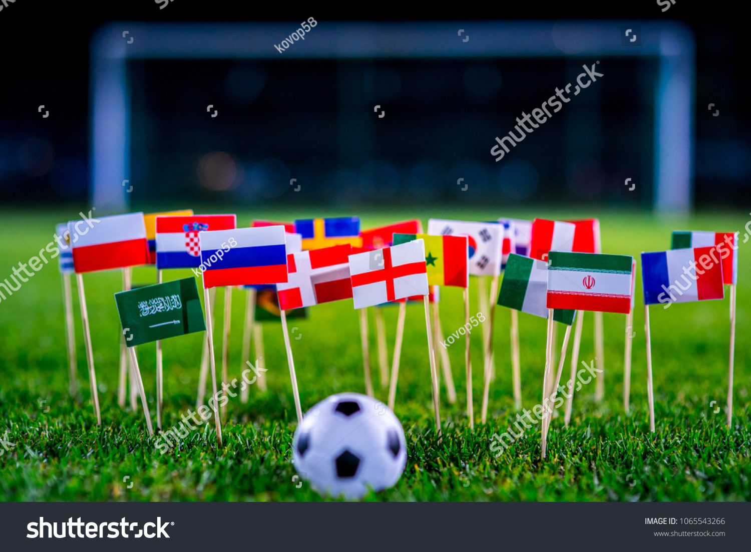 Football ball on green grass and all national flags #1065543266