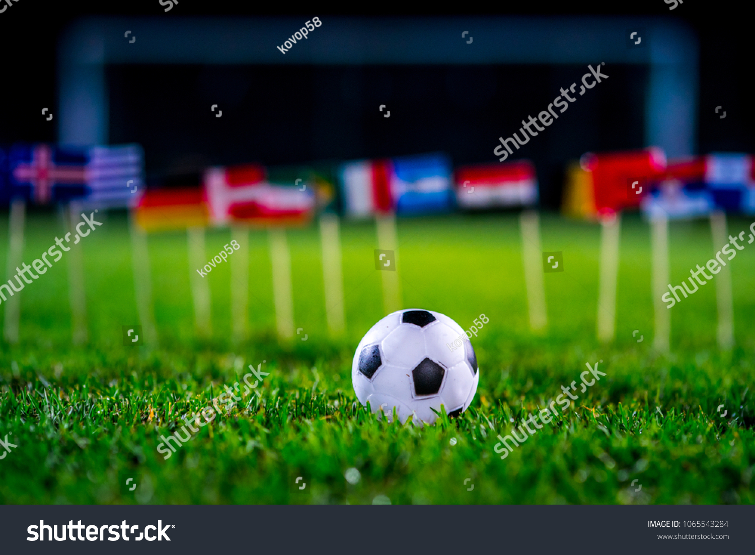 Football ball on green grass and all national flags #1065543284