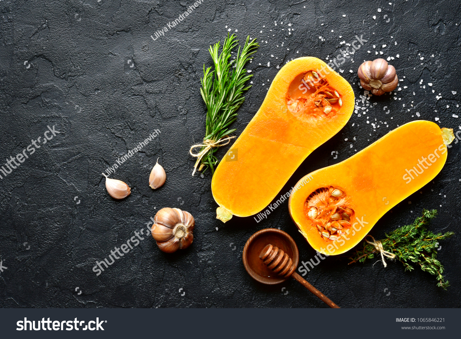 Halves of raw organic butternut squash with spices and ingredients for making on a black slate, stone or concrete background.Top view with copy space. #1065846221