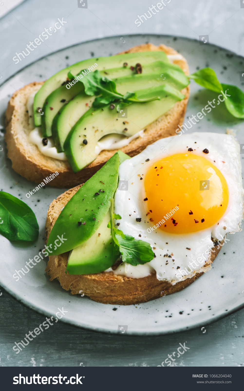 Avocado Sandwich with Fried Egg - sliced avocado and  egg on toasted bread with arugula for healthy breakfast or snack. #1066204040