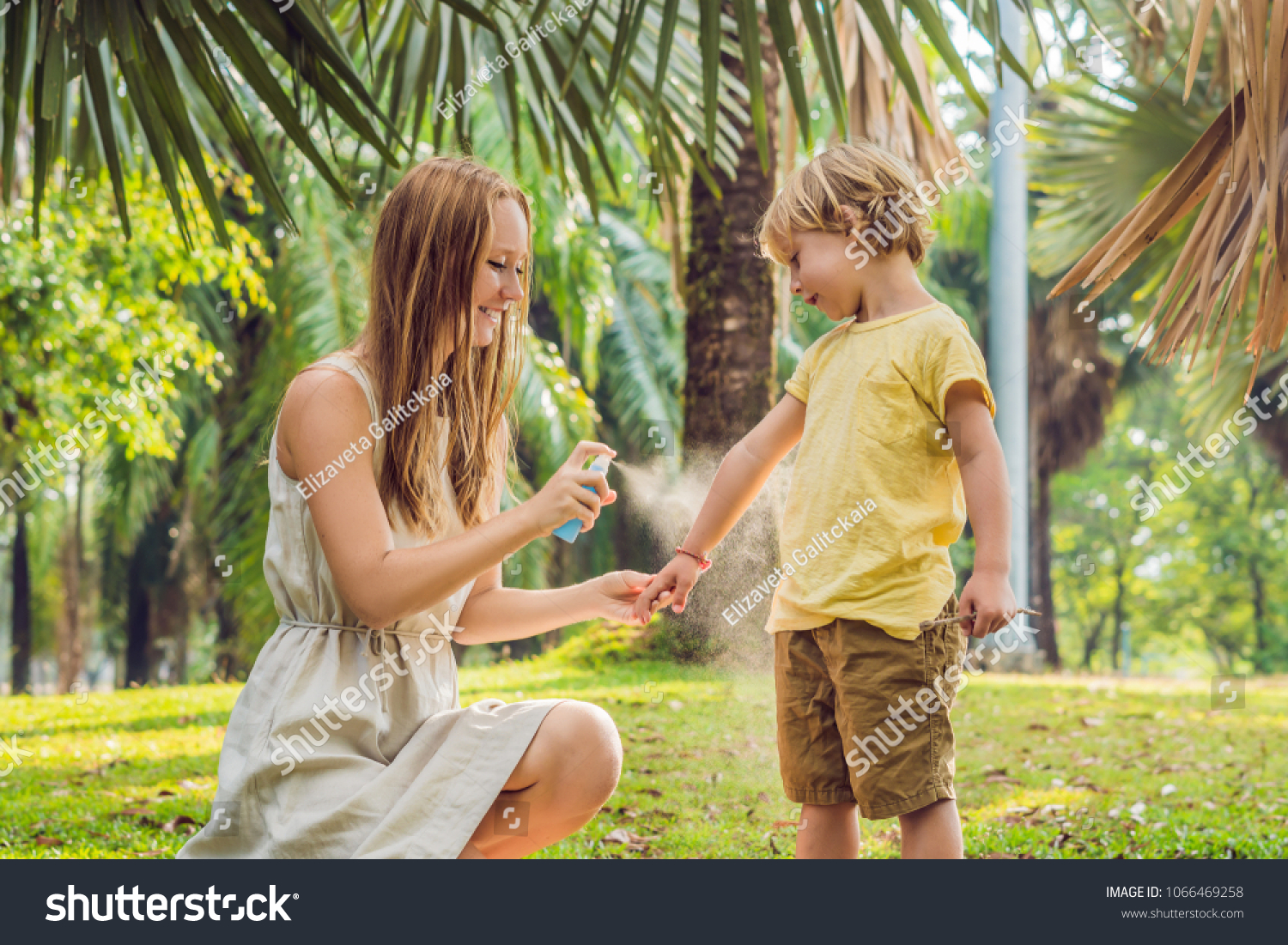 Mom and son use mosquito spray.Spraying insect repellent on skin outdoor #1066469258