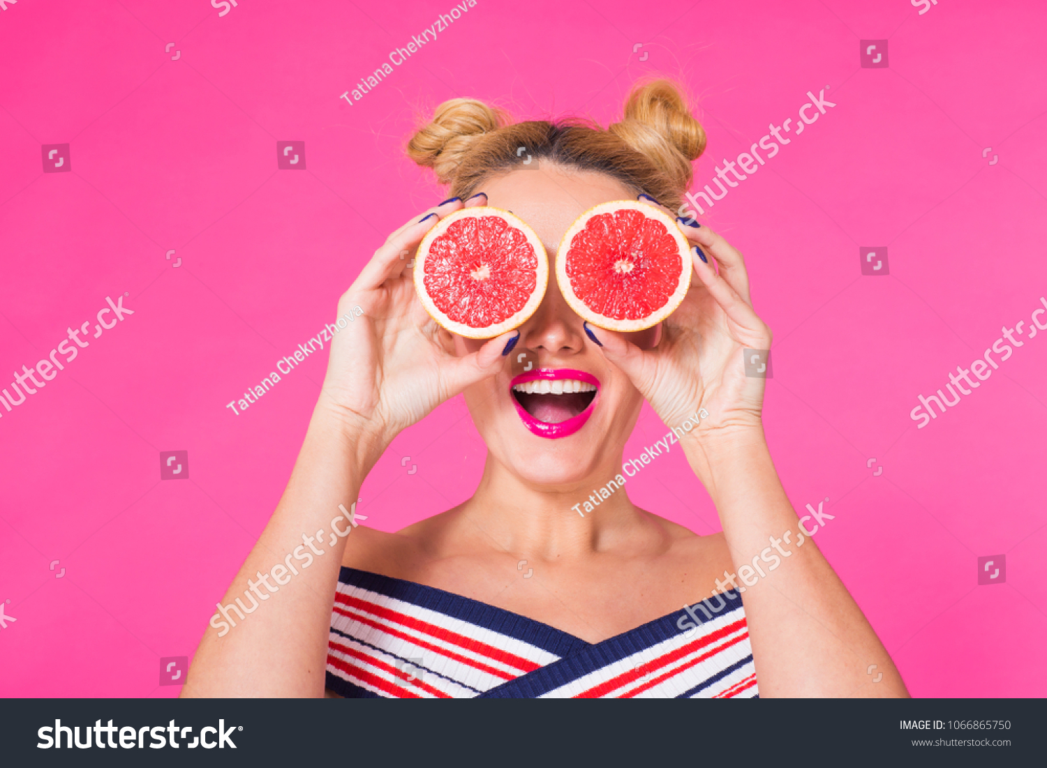 Beauty Model Girl takes Juicy Grapefruit. Beautiful Joyful young girl, funny blonde hairstyle and pink makeup.Holding Orange Slices and laughing, emotions. #1066865750