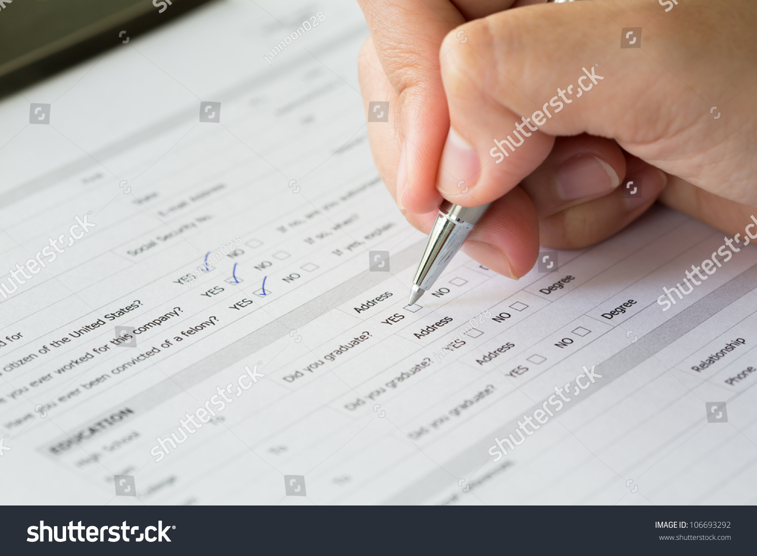 Hand with pen over blank check boxes in application form #106693292