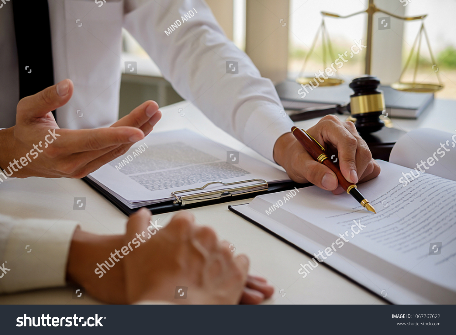 Justice and Law concept. Legal counsel presents to the client a signed contract with gavel and legal law or legal having team meeting at law firm in background #1067767622