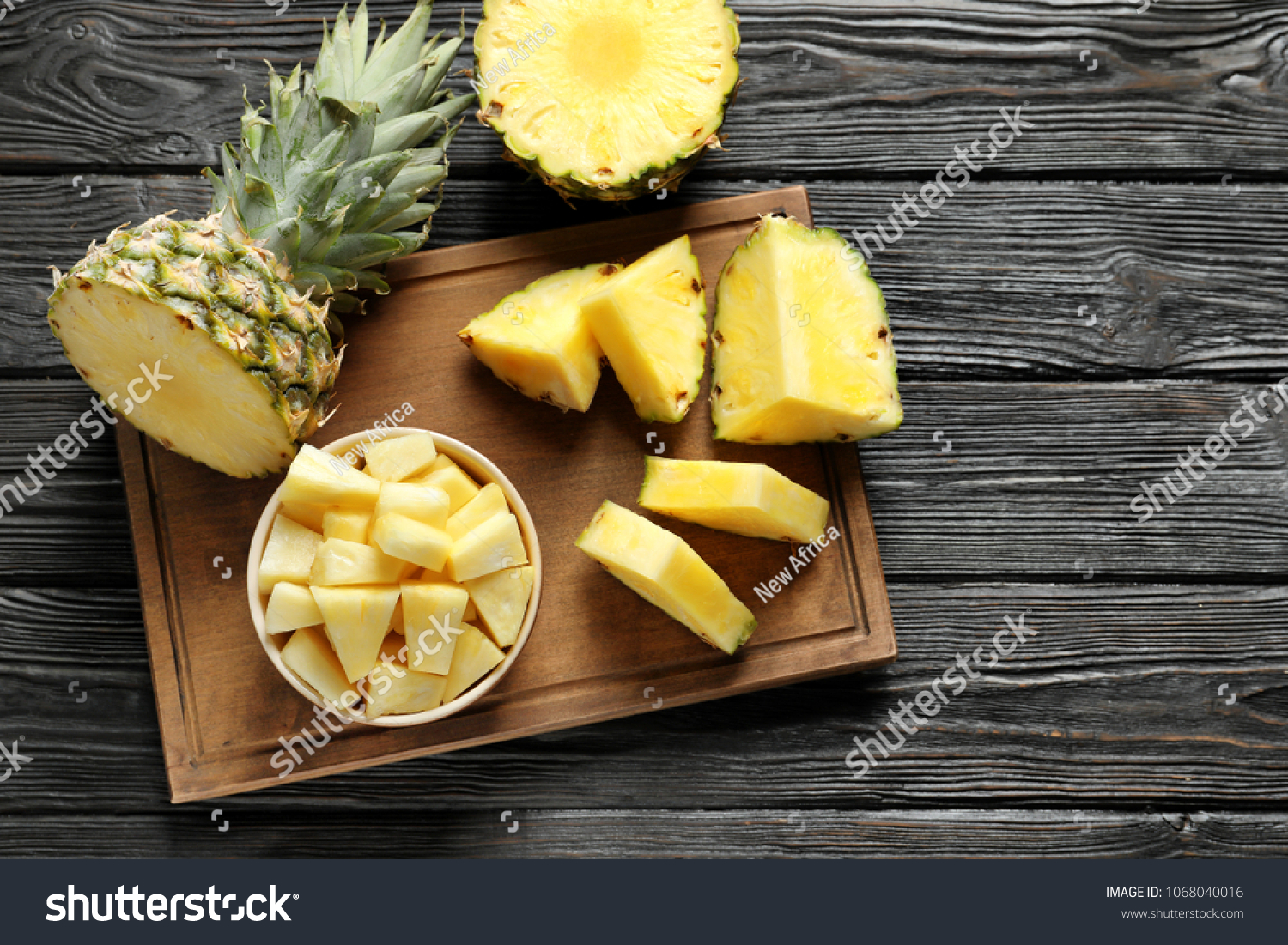 Wooden board with fresh sliced pineapple on table, top view #1068040016