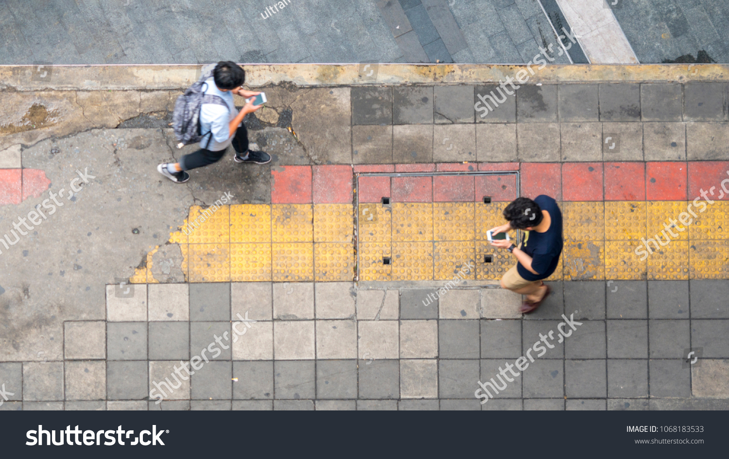 Aerial view and top view with blur man with smartphone is walking in business area with pedestrian street and red and yellow block walkway #1068183533