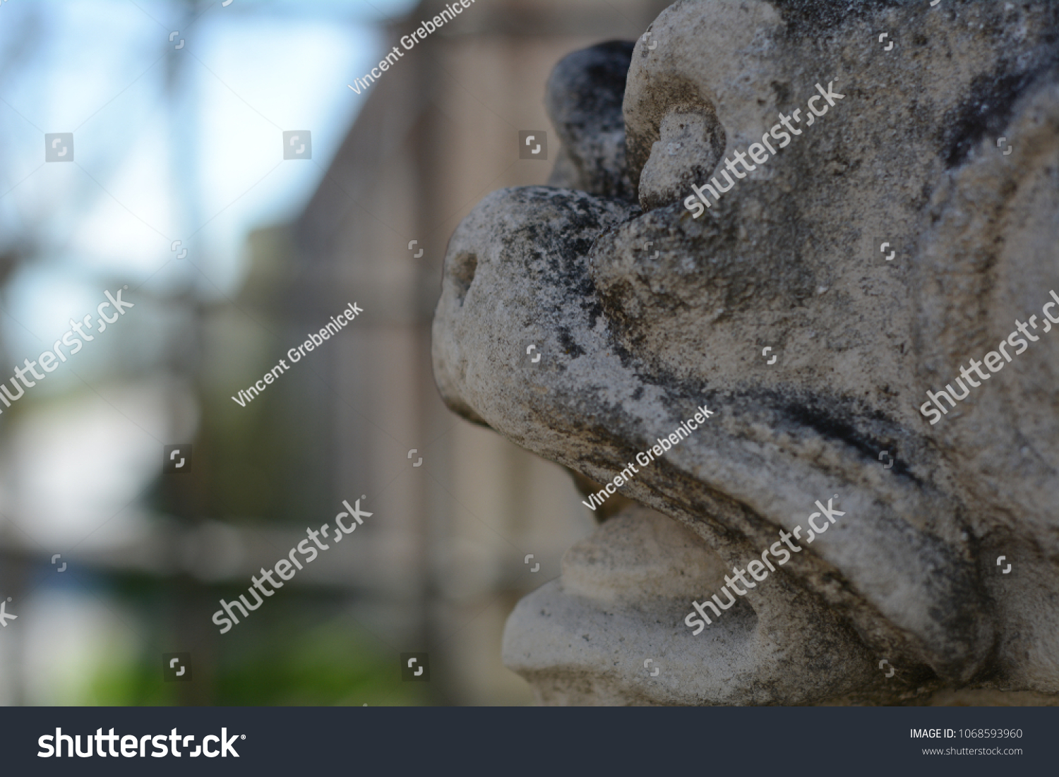 old stone gargoyle head statue in the castle garden in the historical town Mikulov, South Moravia, Czech republic #1068593960