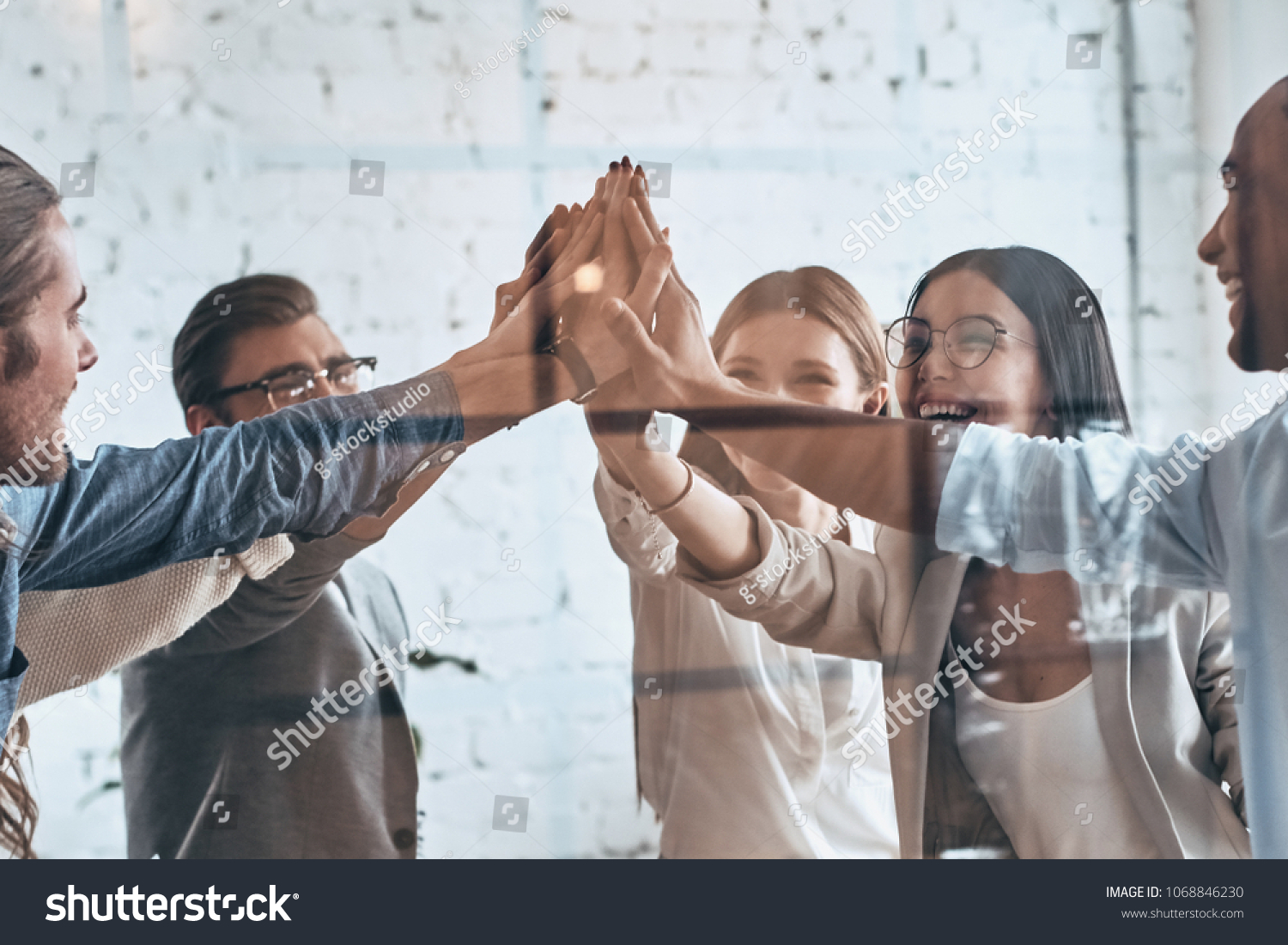 High-five! Group of business colleagues giving each other high-five while working behind the glass wall in the board room #1068846230